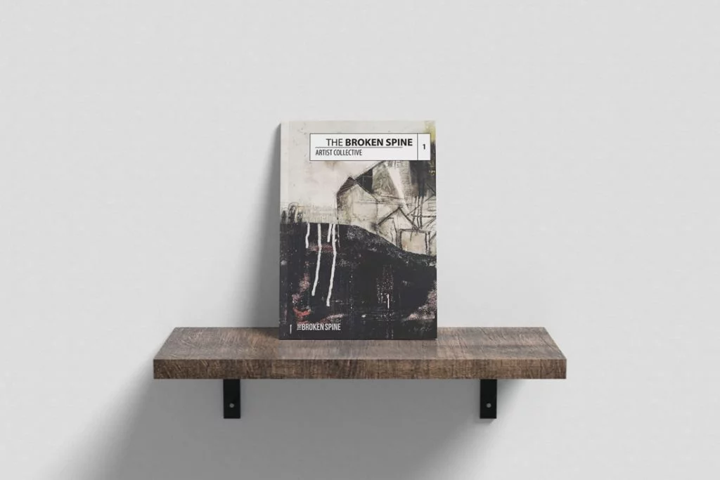 A copy of The Broken Spine Artist Collective on a wooden shelf