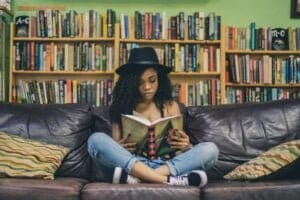 woman reading a book while sitting on black leather 3-seat couch