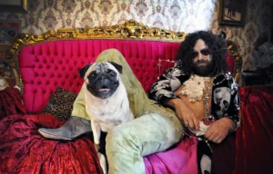 Vanderwolf on a red sofa with a pug, photo by Sin Bozkurt