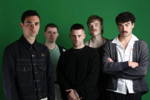 The Murder Capital, five band members, against a green wall