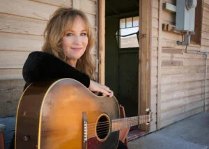 Gretchen Peters leaning on an acoustic guitar