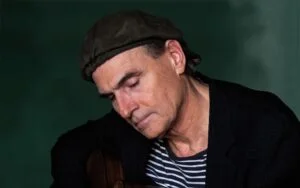 James Taylor in a cap, head bowed