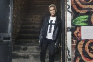 Billy Idol in a leather jacket by a graffiti-covered stairway, photo by Steven Sebring