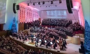 An orchestra and choir performing at Liverpool Philharmonic Hall beside Christmas trees