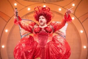 The pantomime dame in a red ruffled costume in the Everyman's Rock 'n' Roll Panto Cinderella