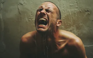 A shirtless man screaming in pain