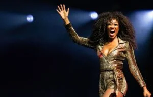 Beverley Knight in a gold sequinned jumpsuit, arm raised on stage