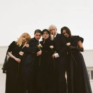 The Last Dinner Party, five members in black holding white roses
