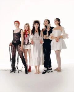 Five women in vintage-style outfits posing against a white background