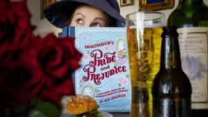A copy of Imaginarium's Pride and Prejudice beside roses and a drink, promotional image