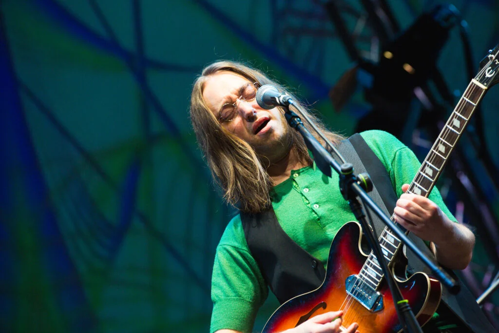 A guitarist in a green top singing in Come Together, photo by Andrew AB Photography