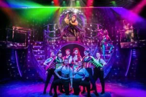 Performers on a neon-lit, glittering stage