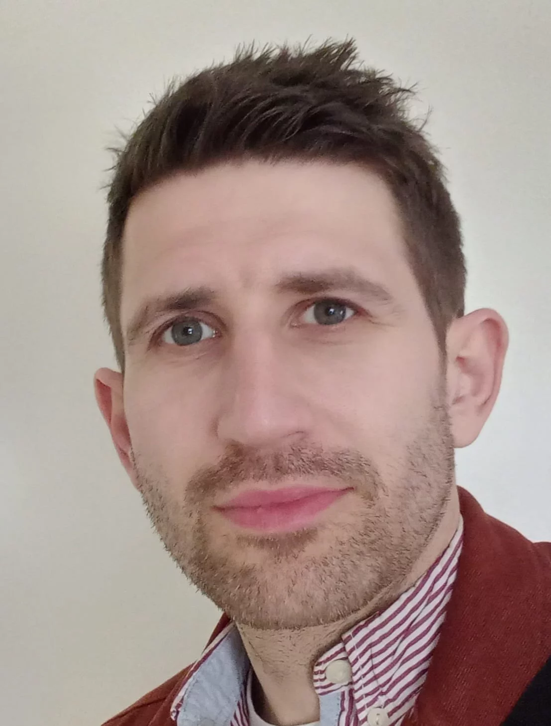 David Hanlon, Co-Poetry Editor at The Broken Spine, in a red cardigan and striped shirt