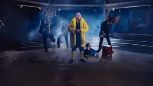 Actors on a misty stage, one in a yellow raincoat, in Twelfth Night at Shakespeare North