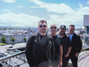 Aslan, four band members, on a rooftop above a city
