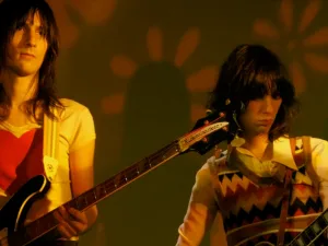 The Lemon Twigs playing guitars in warm orange light