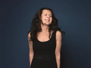 Elkie Brooks in a black top against a blue backdrop