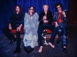 The Darkness, four band members, seated on a red sofa