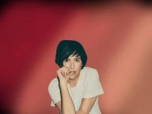 Sharleen Spiteri of Texas, hand to her chin, against a red backdrop