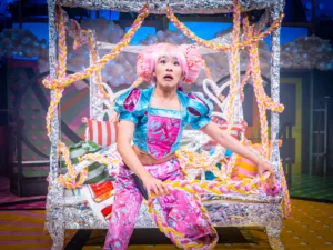An actor as Rapunzel tangled in a long plait in the Everyman panto