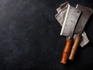 Two meat cleavers on a dark worktop