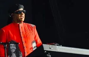 A soul singer in a red jacket and sunglasses at a keyboard