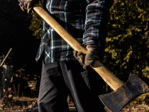 A man in a checked shirt carrying an axe