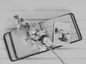 An open diary with a vintage photo and dried flowers, in black and white