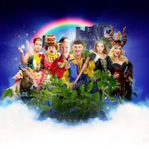 Panto cast in colourful costumes beneath a rainbow, Theatre Royal St Helens