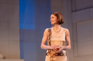 An actor in a 1920s dress holding a glass in The Constant Wife