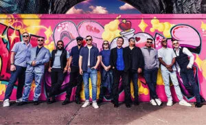 UB40 posing in front of a graffiti-covered wall